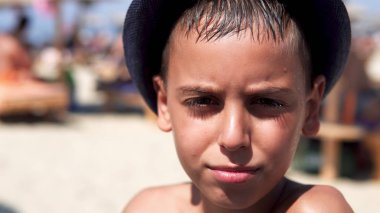 Genç çocuk yaz güneş plaj tarafından kamaştırmak koruma şapkasını giymek ve kameraya gülümse