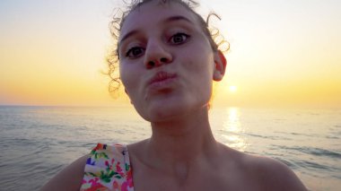 Gün batımında kumsala dönen ve elinde kamera olan gençlerin selfie 'si.