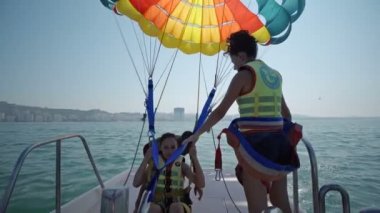 İki kız giymek Sefety kemer önce Parasailing uçuş paraşüt yat tekne ile yaz deniz üzerine çekti çıkar 