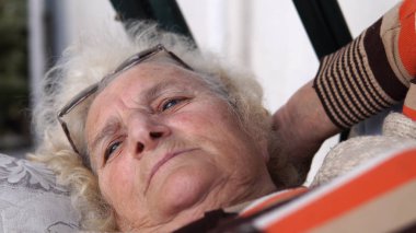 Sundurma salıncak üzerinde rahat yalan gülümseyen yaşlı kadın kıdemli. Sinematik sığ dof