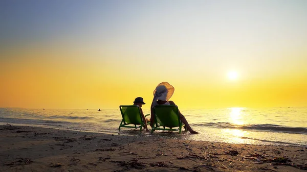 Mor Søn Med Hat Siddende Strandstole Kigger Den Nedgående Sol - Stock-foto