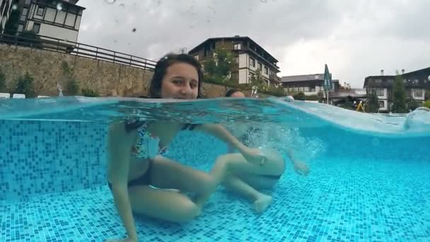 两个朋友在雨天气微笑着在浅水池里玩 对着镜头做鬼脸 戈普罗在水下欣赏半杯视野 慢动作 — 图库视频影像