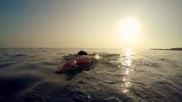 プロスポーツ男は日没 映画のスローモーションのトレッキング ショットで海でクロールを泳ぐ — ストック動画