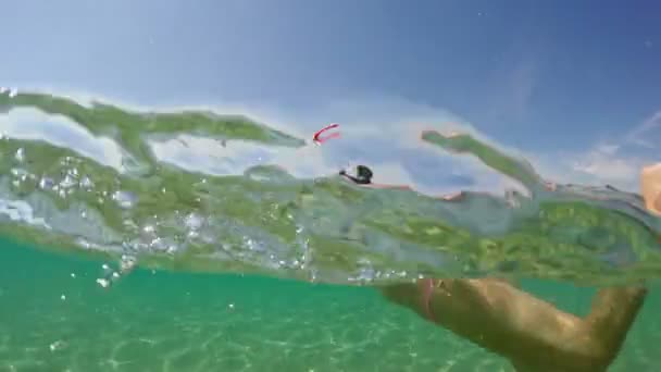 水面をシュノーケリングする10代の少女の後 ゴプロドームの半分水中ビュー — ストック動画