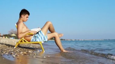 Bir kitap sahilde dalgalar içinde belgili tanımlık geçmiş ile genç adam