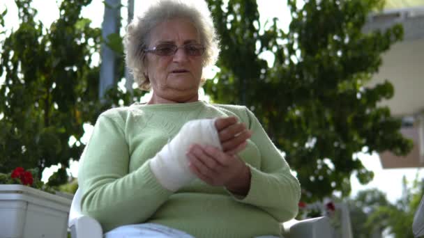 Yaşlı Kadın Yaralı Eline Masaj Yapıyor Oturuyor Sinemasal Olarak — Stok video