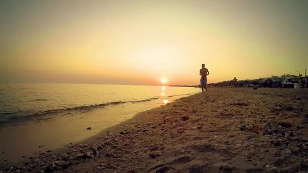 孤独なスポーツ マン日没 スローモーションに対して空の海ビーチでジョギング 実行して — ストック動画
