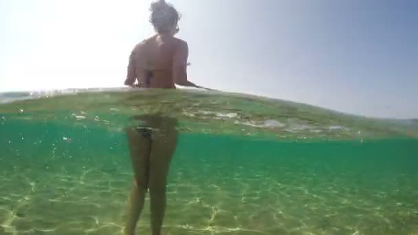 石でビーチの浅い海水を歩くセクシーなファッションモデルの足 ゴプロドームショット — ストック動画