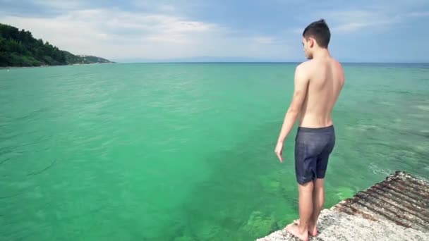 Junger Mann Springt Von Seebrücke Ins Meer — Stockvideo