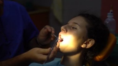 Küçük kıza bir diş diş bir ayna ile inceleyerek diş hekimi