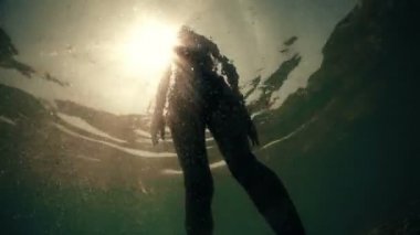 Seksi uygun erkek onu bikini günbatımı güneş, aşağıdan sualtı görünümü karşı uyum sağlıyor.