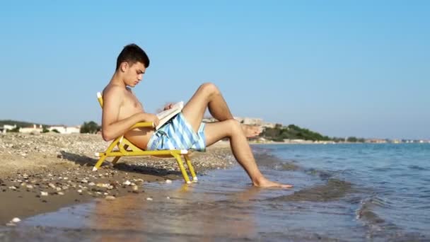 Jonge Mannen Genieten Van Vakantie Aan Kust Lezen Een Boek — Stockvideo