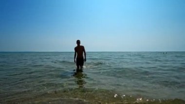 Yakışıklı sporcu erkek, deniz sahilinde sudan çıkıyor. Sinema filmi gibi.