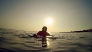 Young man stands on his friend shoulder in sea at sunset, slow motion