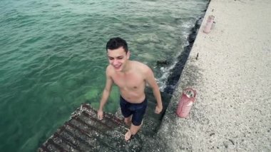 Yakışıklı spor uygun çocuk gel dışarı deniz suyu bağlantı noktası merdivenlerde, yavaş Motiion