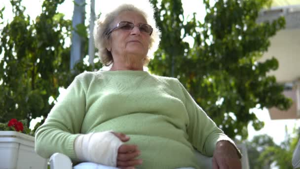 骨折手的老年老妇人坐着说话的画像 — 图库视频影像