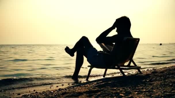 Jungunternehmer Silhouette Beim Lesen Eines Buches Strand Sonnenuntergang Sitzt Stuhl — Stockvideo