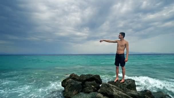 孤身一人站在海岩上 在地平线上航行 — 图库视频影像