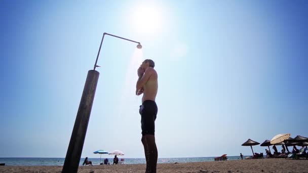 Homem Toma Banho Seu Corpo Chuveiro Praia Contra Sol Tiro — Vídeo de Stock