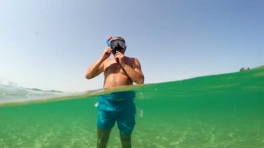 Man put snorkeling mask and swim on sea water surface, gopro half underwater view