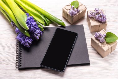 Siyah defter ve akıllı telefon, sümbül çiçekleri ile süslenmiş