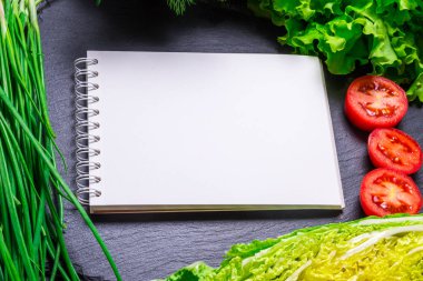 Vejetaryen mutfak masasının üstünde yiyecek ve Kağıt defter