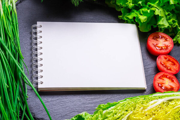 Вегетарианская еда и тетрадь на кухонном столе
