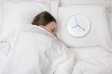 Yatakta uyuyan genç kadın yanındaki büyük bir battaniye ile örtülü