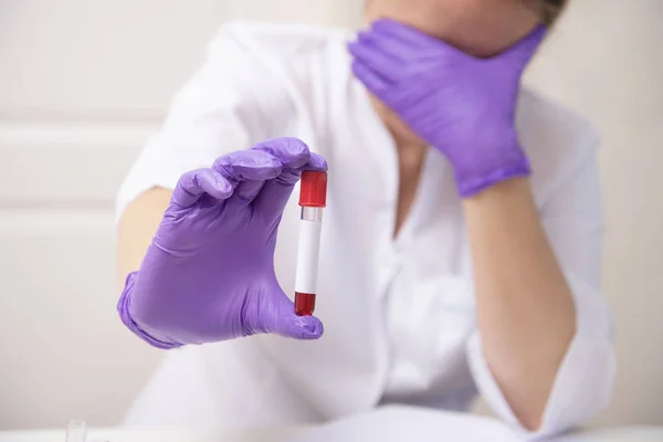 Sad woman holding blood sample tube