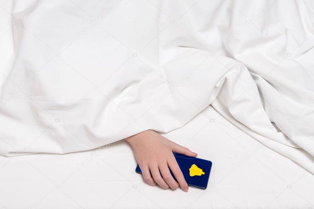 Young girl under the blanket with smart phone in the hand