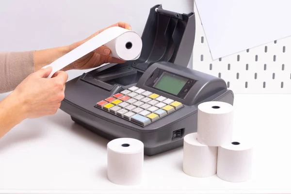 Hands changing roll in Cash Register