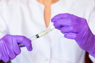 Kadın elleri şırınga ampulünü tutuyor