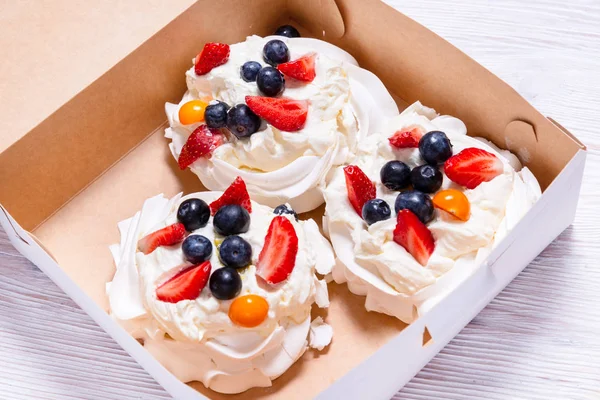 Set weißer Kuchen, Baiser mit Früchten und Beeren im Karton — Stockfoto