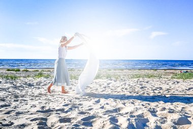 Deniz plajında beyaz sallanan battaniye ile kadın