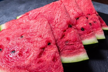 Siyah taş arka plan üzerinde kırmızı tatlı karpuz 