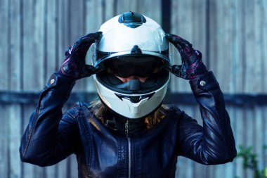 Deri ceketli kadın motosiklet kaskı takıyor