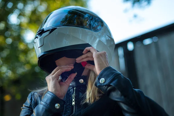 Kobieta stawia na kask motocyklowy i zapięcia zapięcie — Zdjęcie stockowe