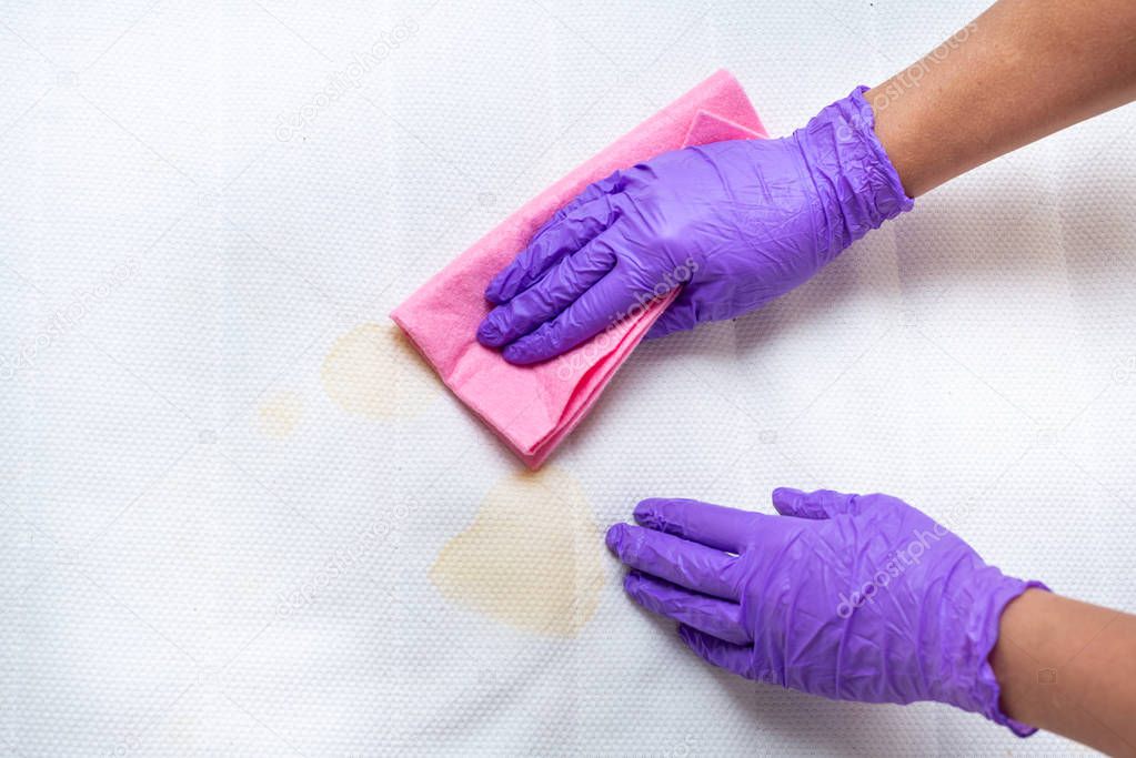 Women hands clean a dirty mattress with stains