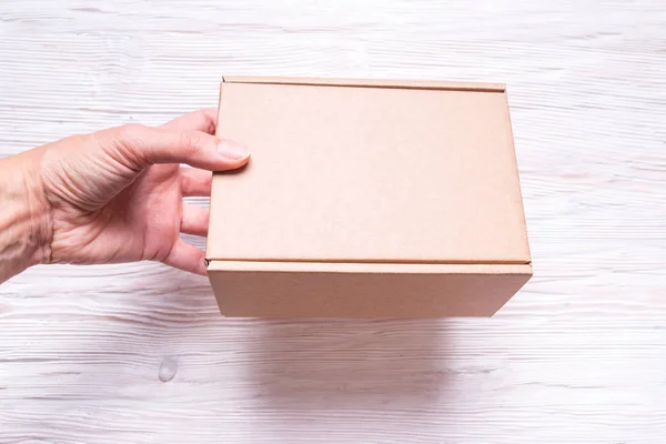 Cardboard box with handle on wooden background — Stock Photo, Image