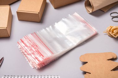 Gri sırt grubunda bir sürü zip kilit çantası ve kahverengi karton kutular var.