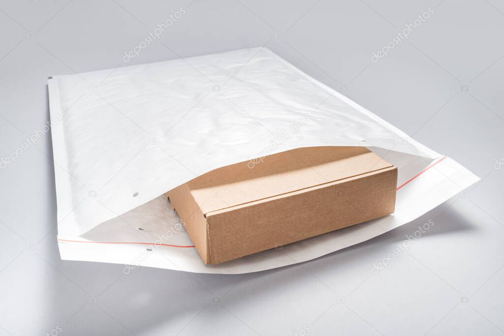 Brown cardboard box packed in white bubble envelopes on grey bac