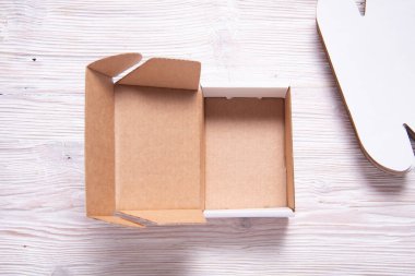 Ahşap arka planda beyaz kare karton kutu, kesilmiş