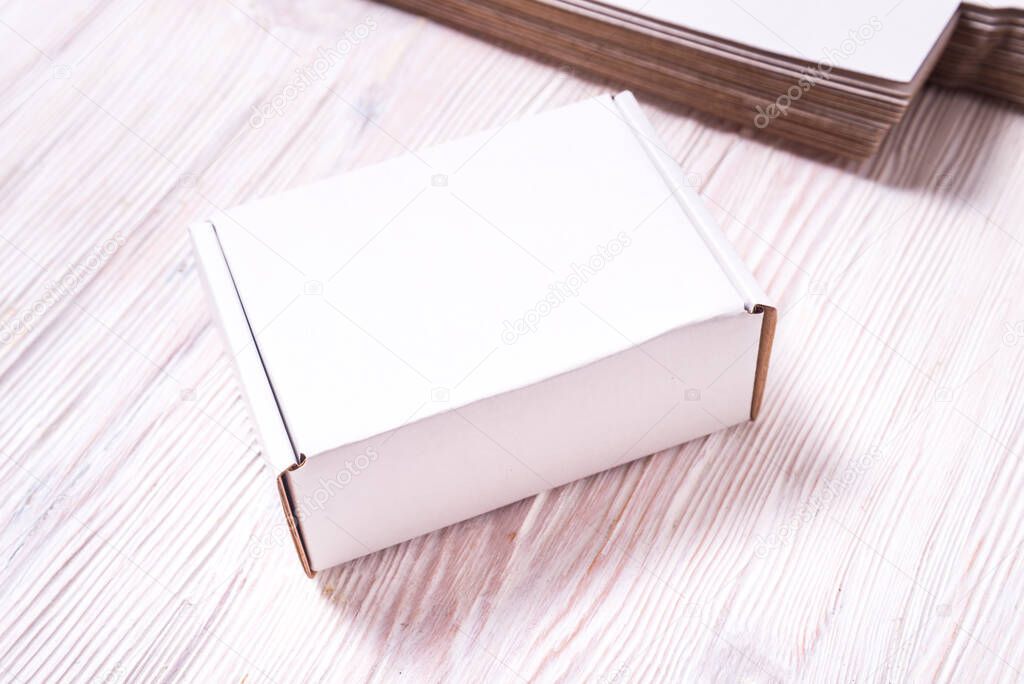 White square carton box on wooden background, cutted