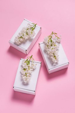 Pembe perde arkasında leylak çiçeklerle süslenmiş hediye kutuları.