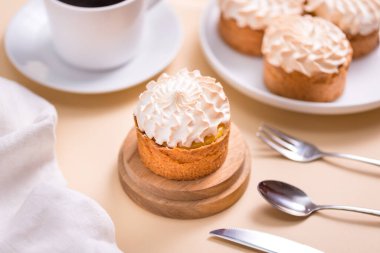 Kremalı tatlı tart ve bej masada bir fincan kahve.