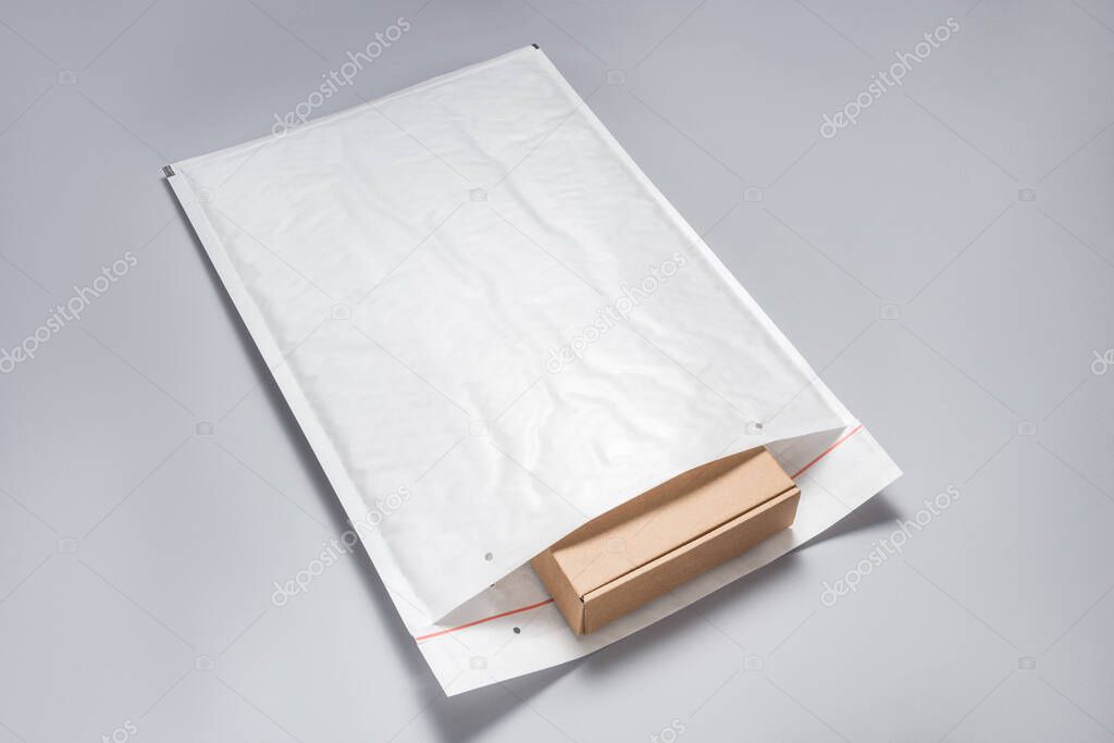 Brown cardboard box packed in white bubble envelopes on grey bac