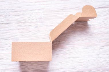 Kahverengi karton kutu, tahta masanın üstünde çanta.