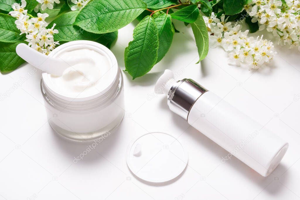 Face cream in jar on white table with bird cherry