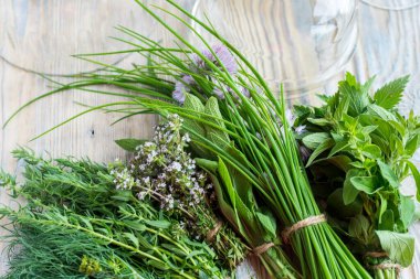 Tahta üzerinde farklı yeşil baharat demetleri var.