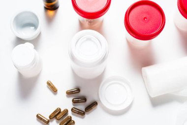 Beyaz masada bir sürü farklı ilaç şişesi var.